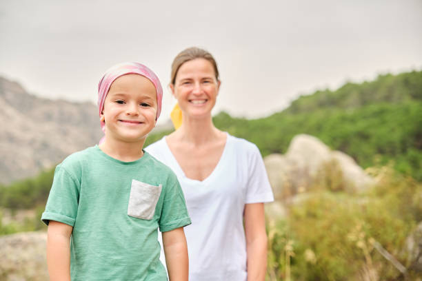 Child in nature with his nurse. The child is wearing a pink scarf on his head. stock photo