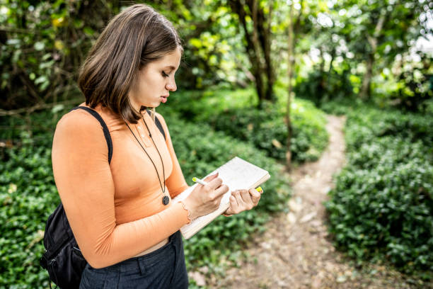 Young woman writing in notepad at public park