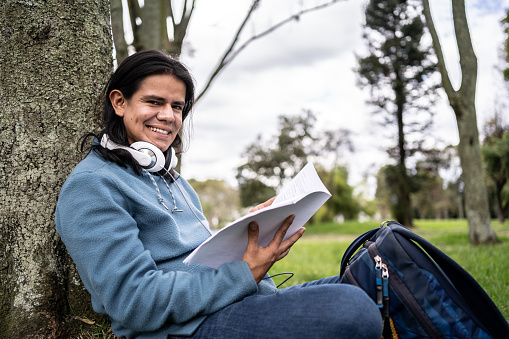 Portrait of a mid adult student studying at public park