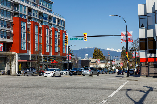 Vancouver, Canada - March 18, 2023:The photo captures a view of the busy intersection of King Edward Street and Cambie Street in Vancouver, with majestic mountains forming a scenic backdrop