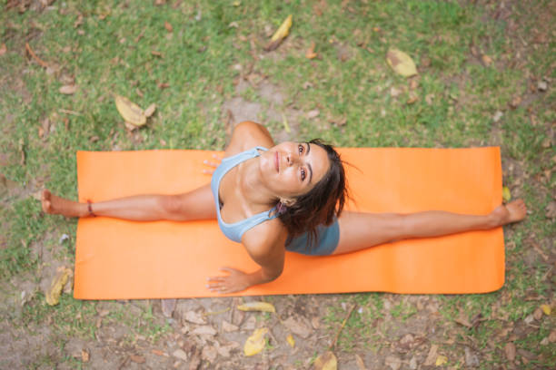 Young woman stretching on her orange mat in the park.