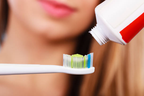 istock Woman applying toothpaste on her toothbrush 1491344470