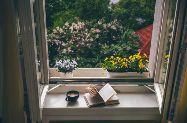 istock Open book and cup of coffee on windowsill in front of the open window 1491348032