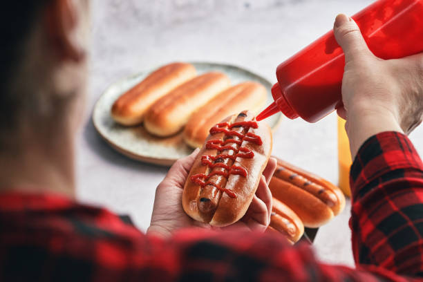 Man's hand holding fresh sausages at a backyard barbecue party
