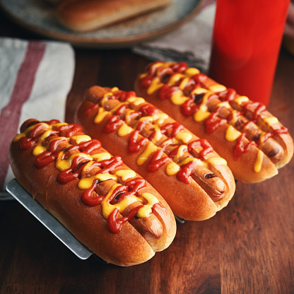 Delicious hot dog is being prepared with mustard and ketchup. The hot dog itself is nestled inside a soft, golden-brown bun, providing a welcoming base for the toppings.