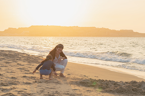 Shot of a young woman spending time at the beach with her adorable daughter, Mother and daughter holding hands, running jumping on sunny beach
