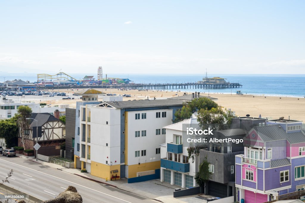 View of Santa Monica beach and pier on a clear autumn morning View of a Santa Monica beach on a partly cloudy autumn morning. Colourful beachfront residential buildings are in foreground. California, USA. Santa Monica Stock Photo