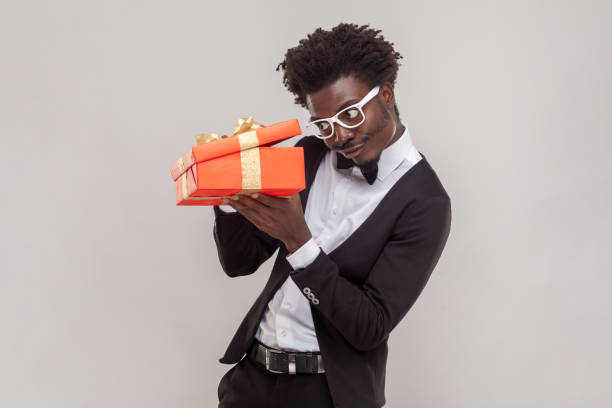 istock Curious handsome young adult man in glasses standing with red gift box, looking inside. 1491350815
