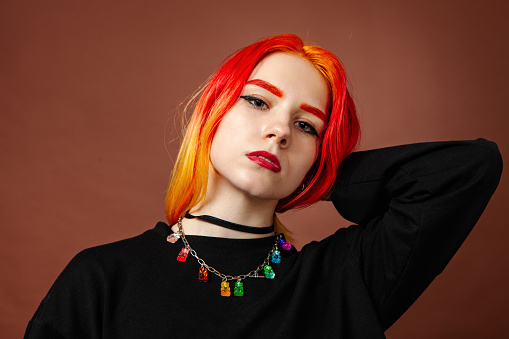 Young white woman with brightly colored hair close-up in the studio on a brown background