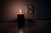 Blackout, candle with a socket, power cut - no electricity, the flame of a candle, circuit breaker, electrical outlet plug