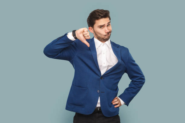 istock Dissatisfied attractive man standing with frowning face, showing thumb up, negative feedback. 1491352495