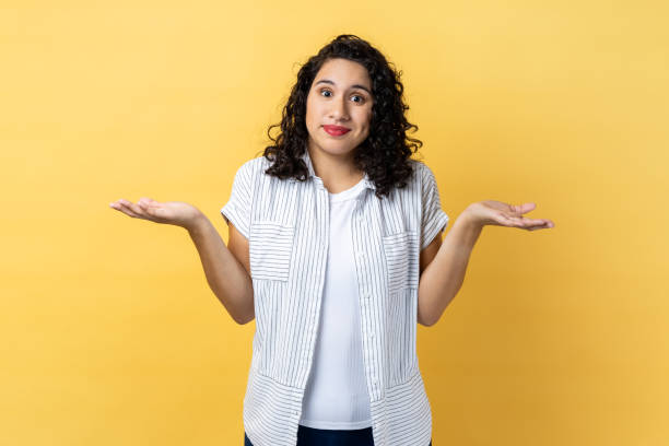 Woman standing with raised arms, looking away and don't know what to do. stock photo