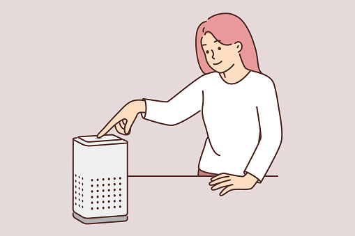 Woman using air purifier turns on electronic device with filter that purifies oxygen from harmful odors. Girl with gadget indoor air purifier adjusts climate control system to maintain comfort