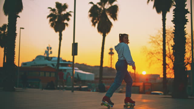 SLO MO Young woman with double ponytails having fun roller skating in the city at sunset