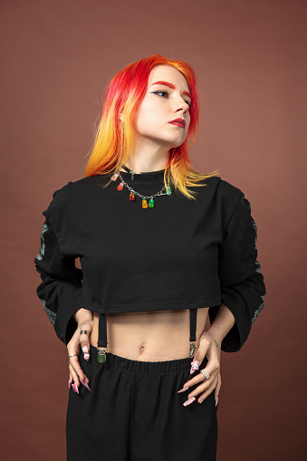 Young white woman with brightly colored hair in the studio on a brown background