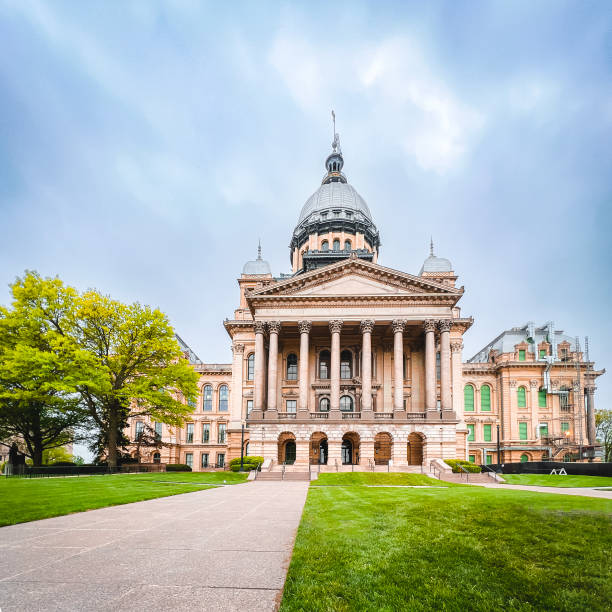 View of the Illinois State Capitol Building in Springfield, Illinois, USA Surface level views of the front facade of the Illinois State Capitol Building. Looking up from the front walkway to the majestic building reaching to the sky. Cloudy blue skies above and lush green trees and lawn surround the building. illinois state capitol stock pictures, royalty-free photos & images
