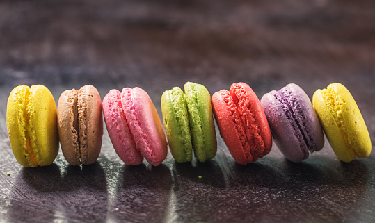 Assorted sweet colorful French macarons with different flavors on a rustic background
