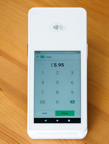Wireless, contactless credit card reader. Electronic payment terminal on wooden surface.