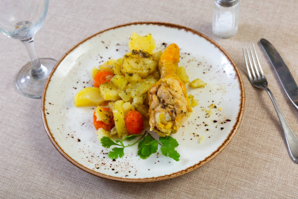 Appetizing gravy baked chicken thigh served with garnish of spicy potatoes stewed with carrots