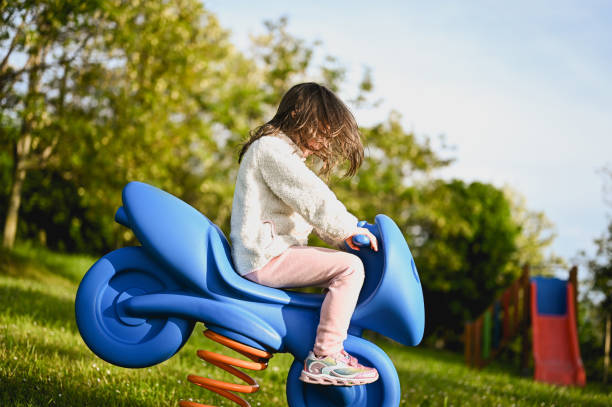 preschool girl using a swing in a natural parkland.