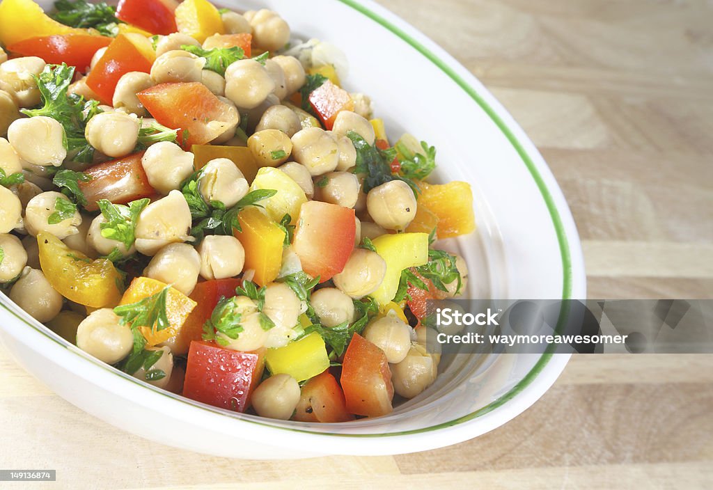 Chick Pea Salad Chick pea salad in a bowl sitting on a wooden table. Bean Stock Photo