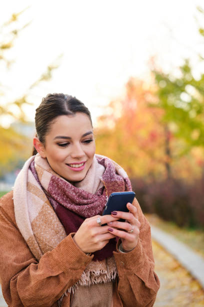 istock Caucasian woman using the phone smiling in autumn. 1491372456