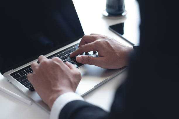 istock Businessman working on laptop computer on white table at office. Business man hands typing on laptop, online working, surfing the internet, close up 1491373293