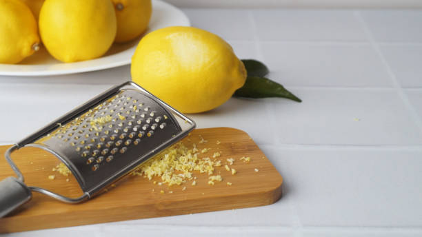 istock Wooden board with grater and fresh lemon zest on white tiled table, space for text 1491378129