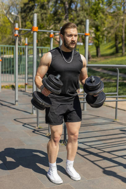 istock Athletic man doing arms weight lifting dumbbells exercises, pumping up arm bicep muscles outdoors 1491388859