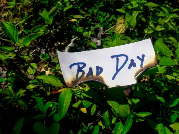 Photo of bad day writing on burnt white paper on green grass