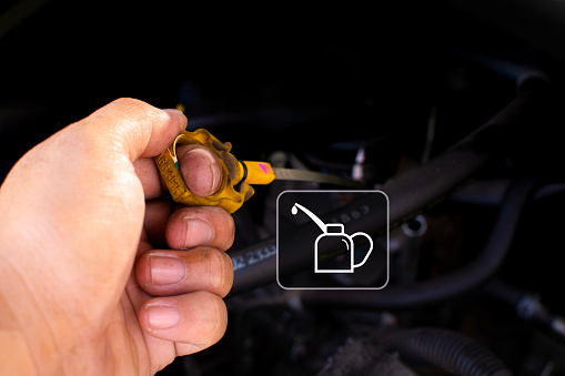 A mechanic check the car engine oil level by pulling the dipstick, motor oil symbol, copy space, Car maintenance service concept.