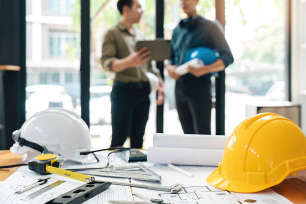 Engineer teams meeting working together holding worker helmets on construction site in modern city.Asian industry professional team