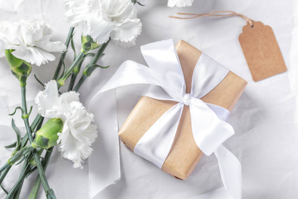 istock Gift box wrapped in craft paper with white bow and flowers  background 1491410823