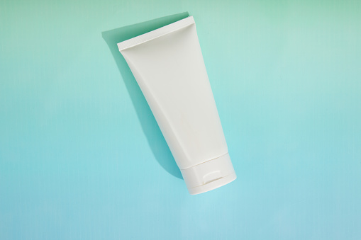 Top view of white plastic bottle without label container cream or facial cleanser on pastel background. Mockup for design cosmetic, branding product. Minimal, space for design