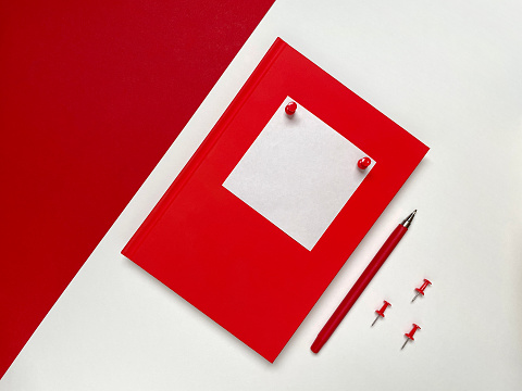 Red notepad with red stationery on colored background. Top view, flat lay.
