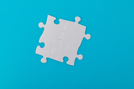 Four pieces of blank jigsaw puzzle on blue background.