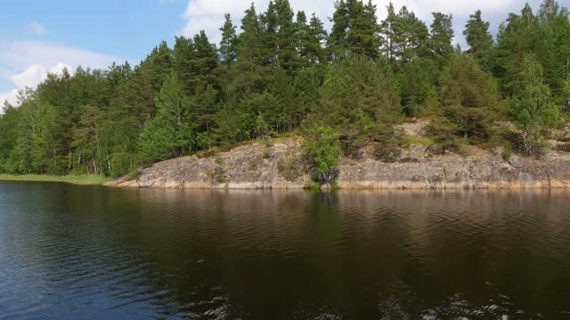 Untouched nature of Karelian skerries, view from boat on rocky shore and forest