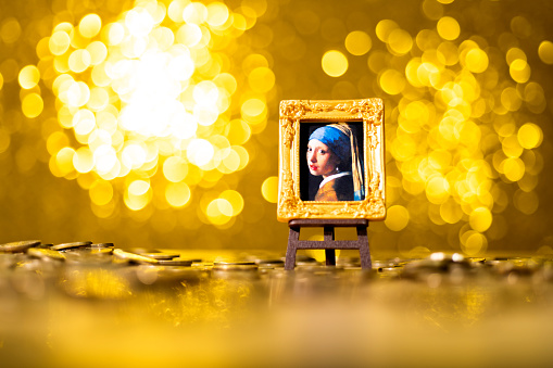 Fujian, China - December 28, 2021: A miniature replica of Girl with a pearl earring  is in front of the golden background. The girl with pearl earrings is an oil painting created by Johannes Vermeer, a Dutch painter in the 17th century, in 1665. It is one of Johannes Vermeer's representative works. It is now collected in the moritis Royal Art Museum in the Hague, the Netherlands.