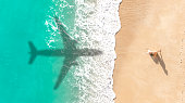 Airplane shadow flying over tropical beach.
