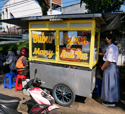 A traditional Indonesian Street Push Food Cart selling Bubur Ayam or chicken porridge in Bandung, West Java, Indonesia. Bubur ayam food carts usual sell the porridge in the morning time for breakfast. Customer are waiting for their orders.