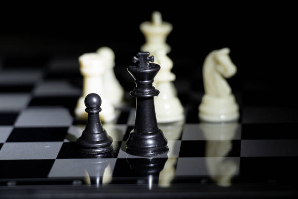 istock chess pieces on a chessboard in a dark room illuminated by a lamp 1491426414