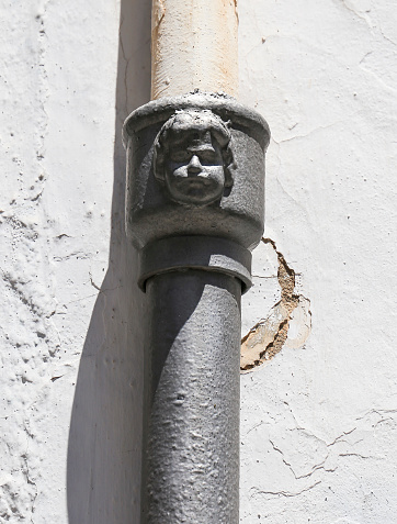 Face on old forged metal gutter in Javea town. Modernist style
