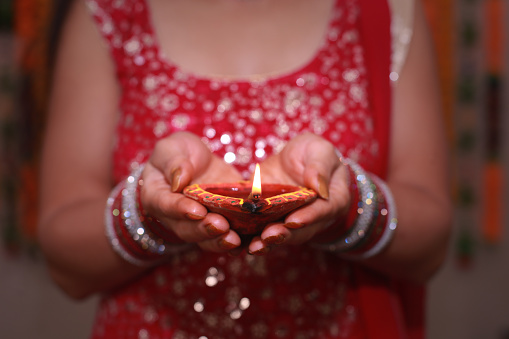 Unrecognizable women holding oil lamp in hand on Diwali festival. Diwali, also known as Deepavali or the Festival of Lights, is one of the most important festivals in Indian religions. It symbolises the spiritual \
