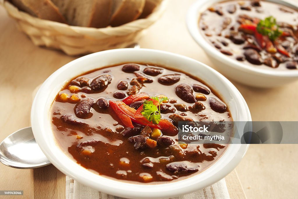 Chilli con carne with sweet corn in a white bowl Chilli con carne with red pepper and parsley Two Objects Stock Photo