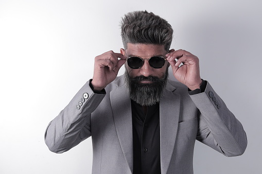 Portrait of a happy South Indian bearded man wearing suit and goggles. stylish man in different poses and expressions. Coat and pant.