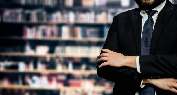 istock Black suit-clad businessman standing with confidence at library. Equilibrium 1491432823