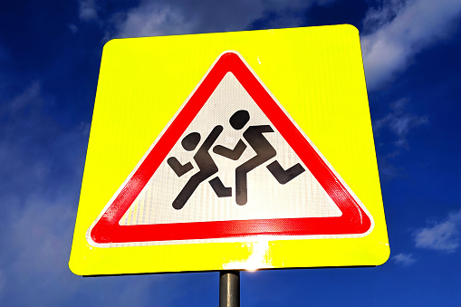 Road sign children's crossing, close-up on a blue sky background