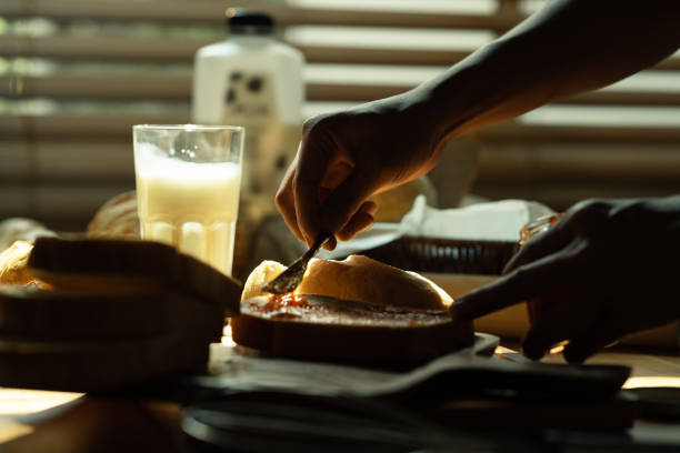 istock Closeup shot of unrecognizable spreading raspberry jam on slice of bread with table knife. 1491438316