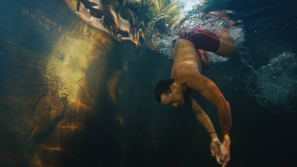 istock Man dives in the freshwater river with sunny rays shining through the water 1491438468