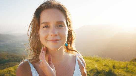 Portrait of the young caucasian woman outdoor at sunrise. Model looks into the camera
